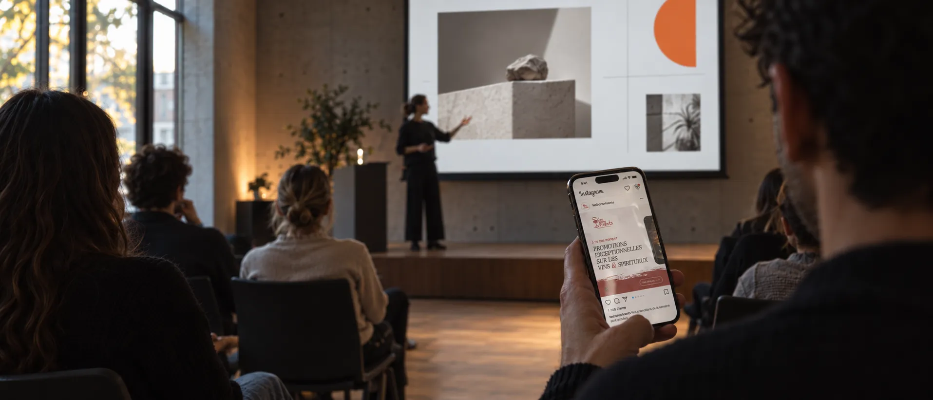 Salle de conférence : une intervenante présente une slide sur grand écran, tandis qu’un spectateur fait défiler sur son téléphone un post Instagram des Bons Vivants.